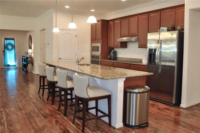 a kitchen with kitchen island granite countertop a table chairs refrigerator a sink and a counter space