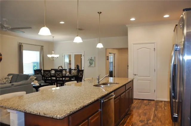 a kitchen with granite countertop a sink a counter top space and living room view