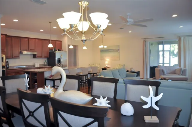 a dining room with wooden floor a chandelier a glass table and chairs