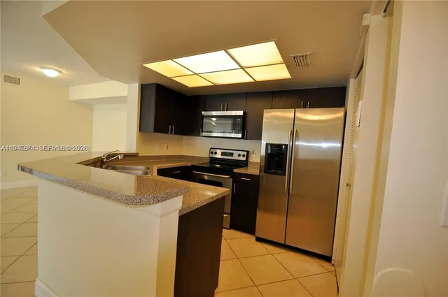 a kitchen with stainless steel appliances granite countertop a sink a stove and a refrigerator
