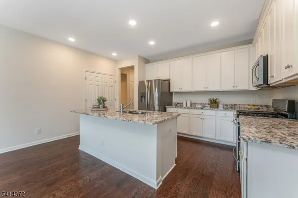 a kitchen with kitchen island granite countertop a sink cabinets and wooden floor