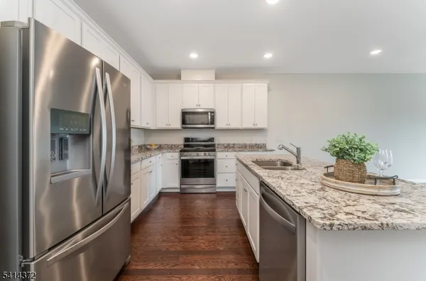 a kitchen with stainless steel appliances granite countertop a refrigerator sink and stove