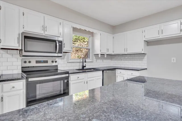 a kitchen with stainless steel appliances granite countertop a sink a stove and microwave