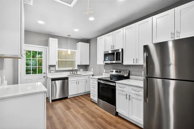 a kitchen with white cabinets and stainless steel appliances