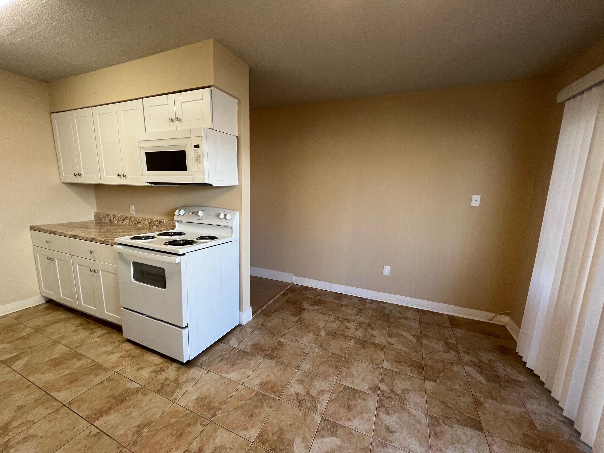 210 Pelham Road, Unit 105B Fort Walton Beach, FL 32547 - Photo 17 of 41 a white kitchen with stainless steel appliances a white cabinet and a stove top oven