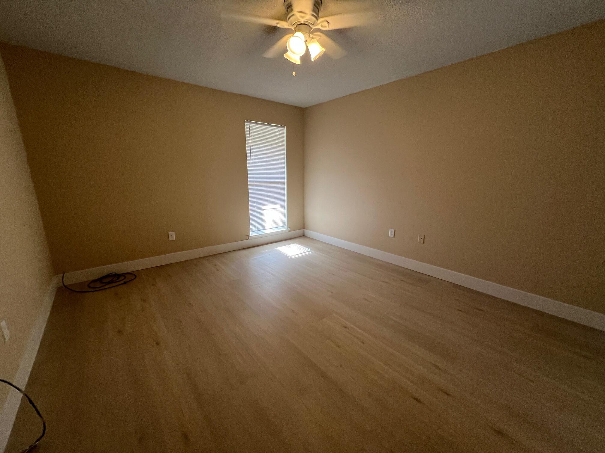 210 Pelham Road, Unit 105B Fort Walton Beach, FL 32547 - Photo 27 of 41 an empty room with wooden floor chandelier fan and windows