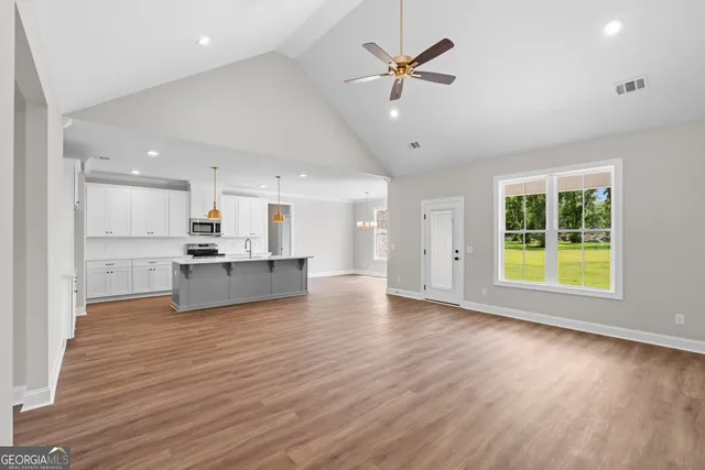 a view of open kitchen with wooden floor and a ceiling fan