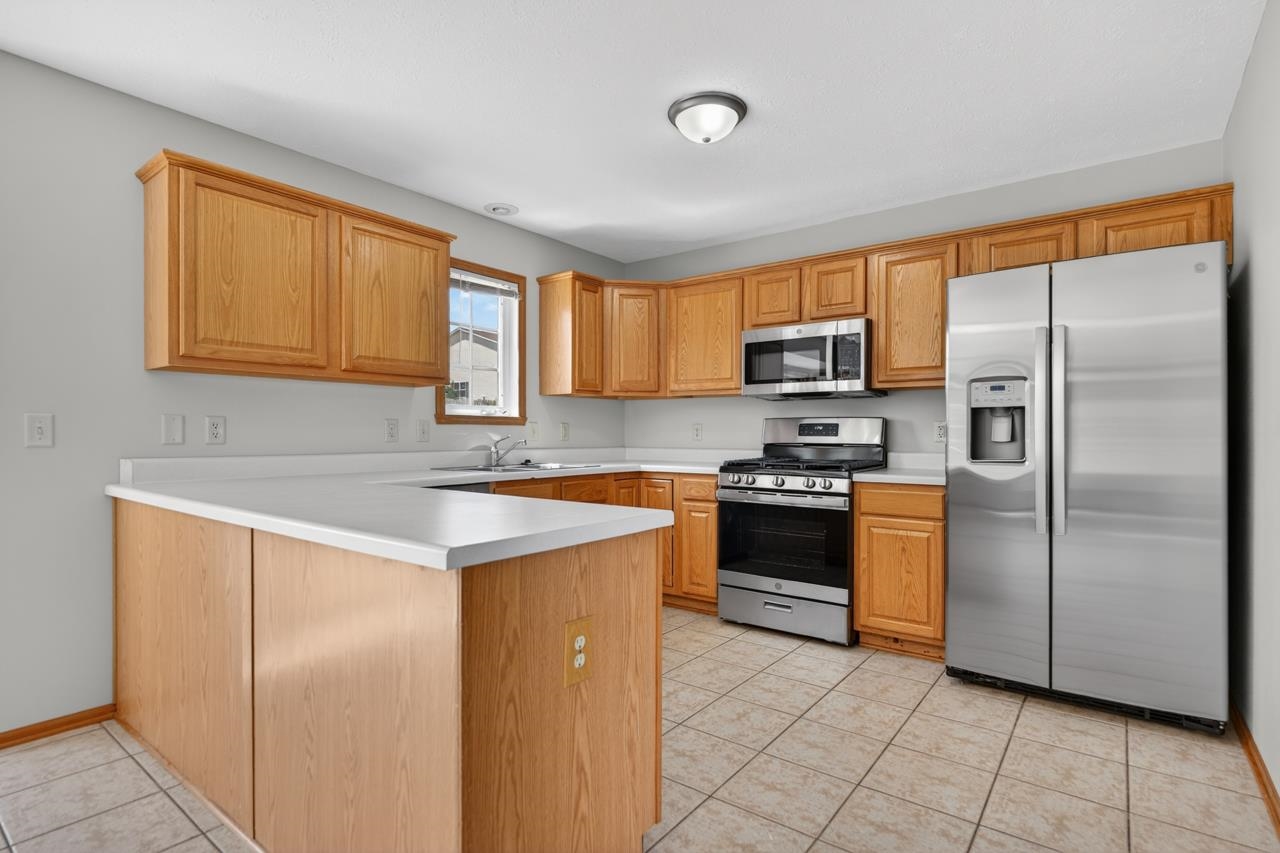676 Elberon Way Roscoe, IL 61073 - Photo 11 of 30 a kitchen with granite countertop a refrigerator stove top oven a sink and dishwasher