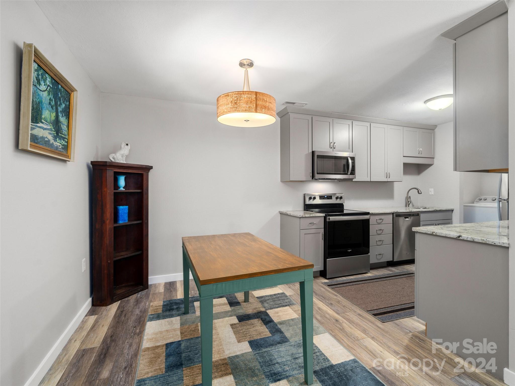 111 Shepard Square, Unit 608 Brevard, NC 28712 - Photo 5 of 29 a kitchen with granite countertop a stove top oven a sink dishwasher a dining table and chairs with wooden floor