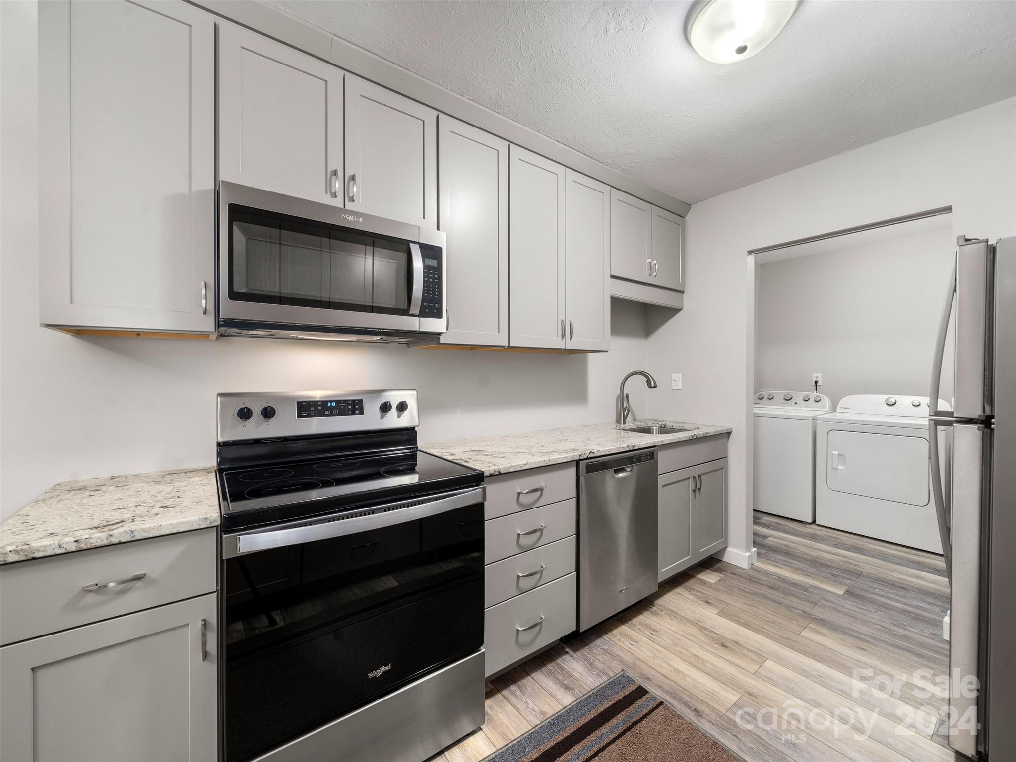 111 Shepard Square, Unit 608 Brevard, NC 28712 - Photo 7 of 29 a kitchen with white cabinets and stainless steel appliances