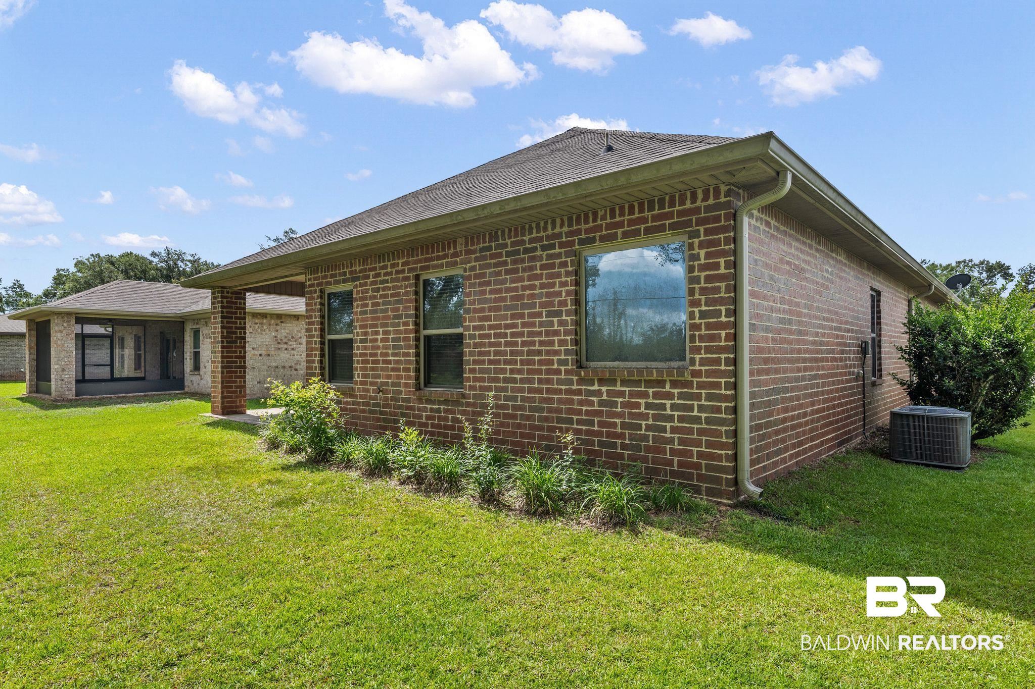 1464 Surrey Loop Foley, AL 36535 - Photo 24 of 24 View of side of home with brick siding, a yard, and a shingled roof