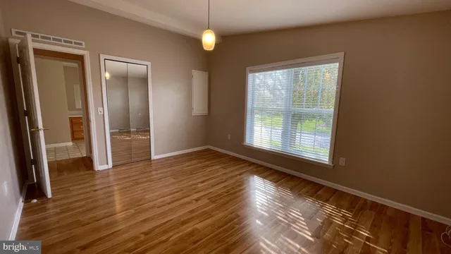 a view of an empty room with wooden floor and a window