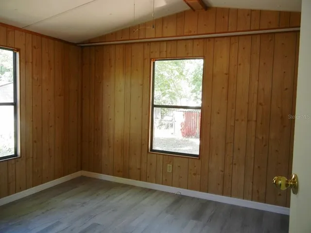 an empty room with wooden floor closet and windows