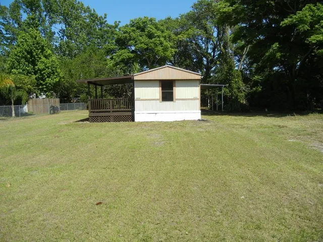 a front view of house with yard and trees in the background