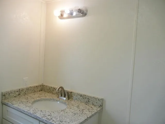 a bathroom with a granite countertop sink and vanity