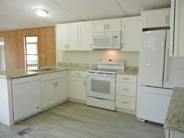 a kitchen with white cabinets white stainless steel appliances and sink