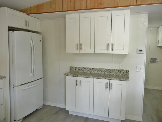 a kitchen with stainless steel appliances granite countertop white cabinets and a refrigerator