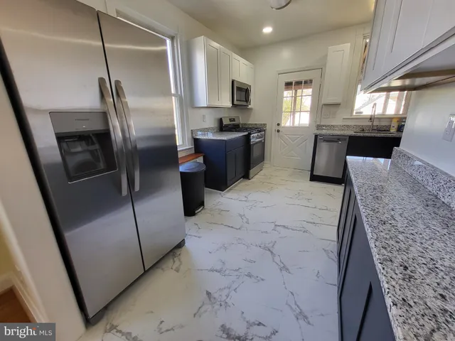 a kitchen with stainless steel appliances granite countertop a refrigerator a sink a stove and a refrigerator