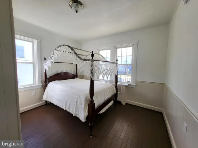 a view of a hallway with wooden floor and a bathroom