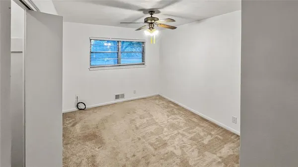 an empty room with a ceiling fan and a window