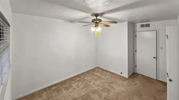 an empty room with a chandelier fan and closet
