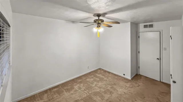an empty room with a chandelier fan and closet