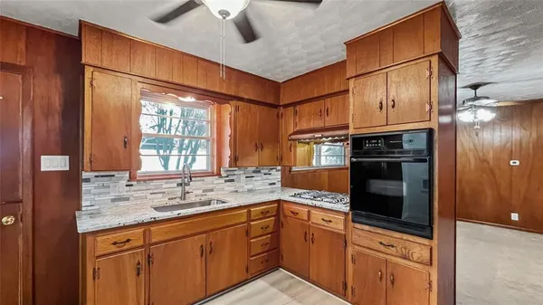 a kitchen with stainless steel appliances granite countertop a sink window and cabinets