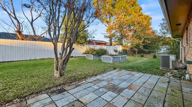 a view of a backyard with brick wall and a large tree