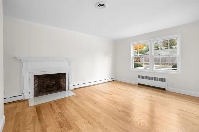 an empty room with windows and fireplace