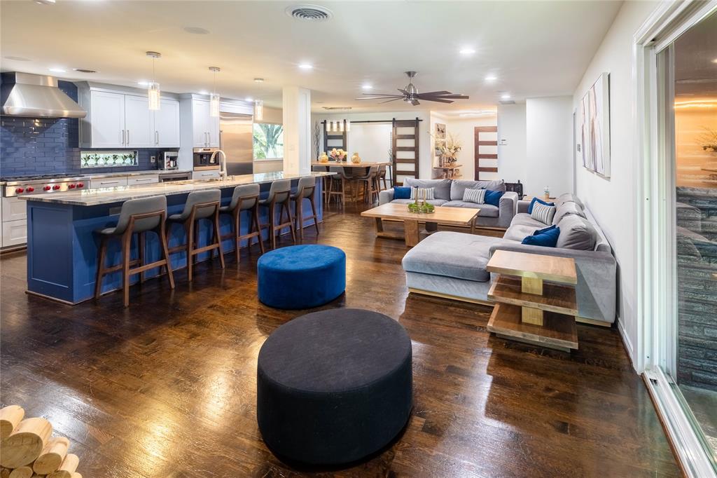 Living area with wood burning brick fireplace, breakfast bar, wood flooring, open to dining, kitchen and office.