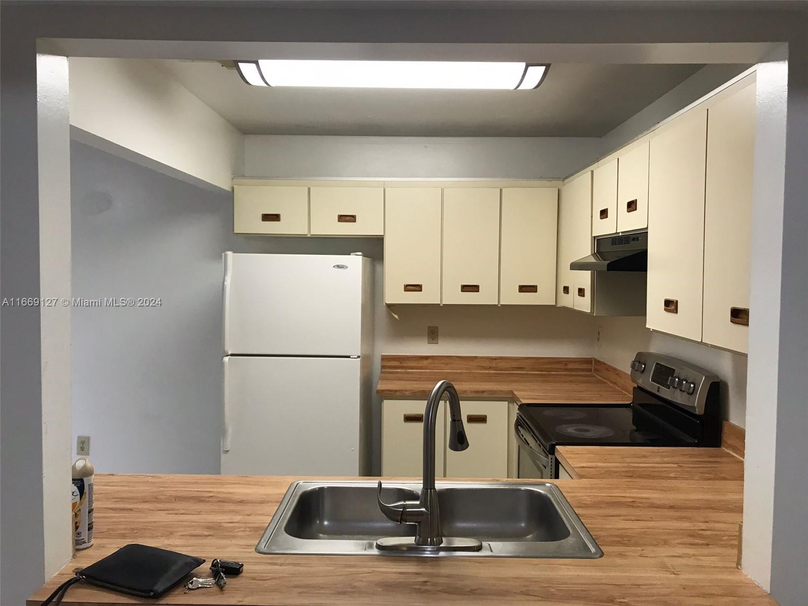 423 Northeast 210th Cir Terrace, Unit 10425 Miami, FL 33179 - Photo 11 of 37 a kitchen with kitchen island a counter top space a sink and a stove