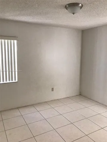 a view of an empty room with window and a bathroom