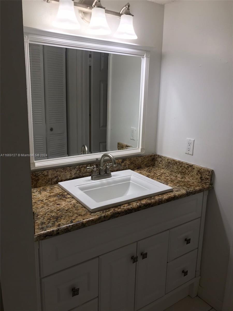 423 Northeast 210th Cir Terrace, Unit 10425 Miami, FL 33179 - Photo 33 of 37 a bathroom with a granite countertop sink and mirror
