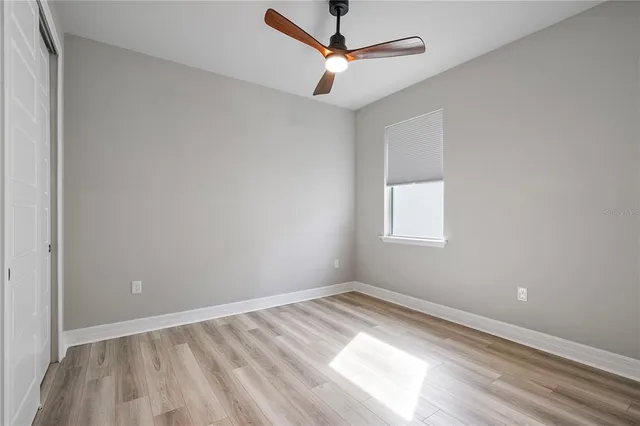 a view of empty room with wooden floor and fan