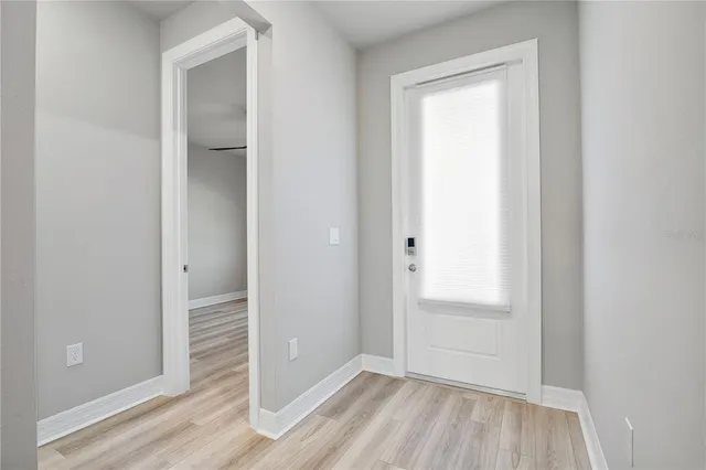an empty room with wooden floor closet and windows
