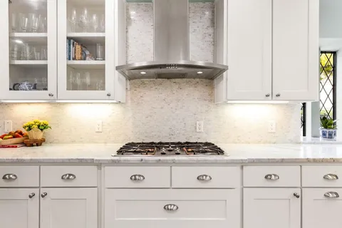 a kitchen with white cabinets and window