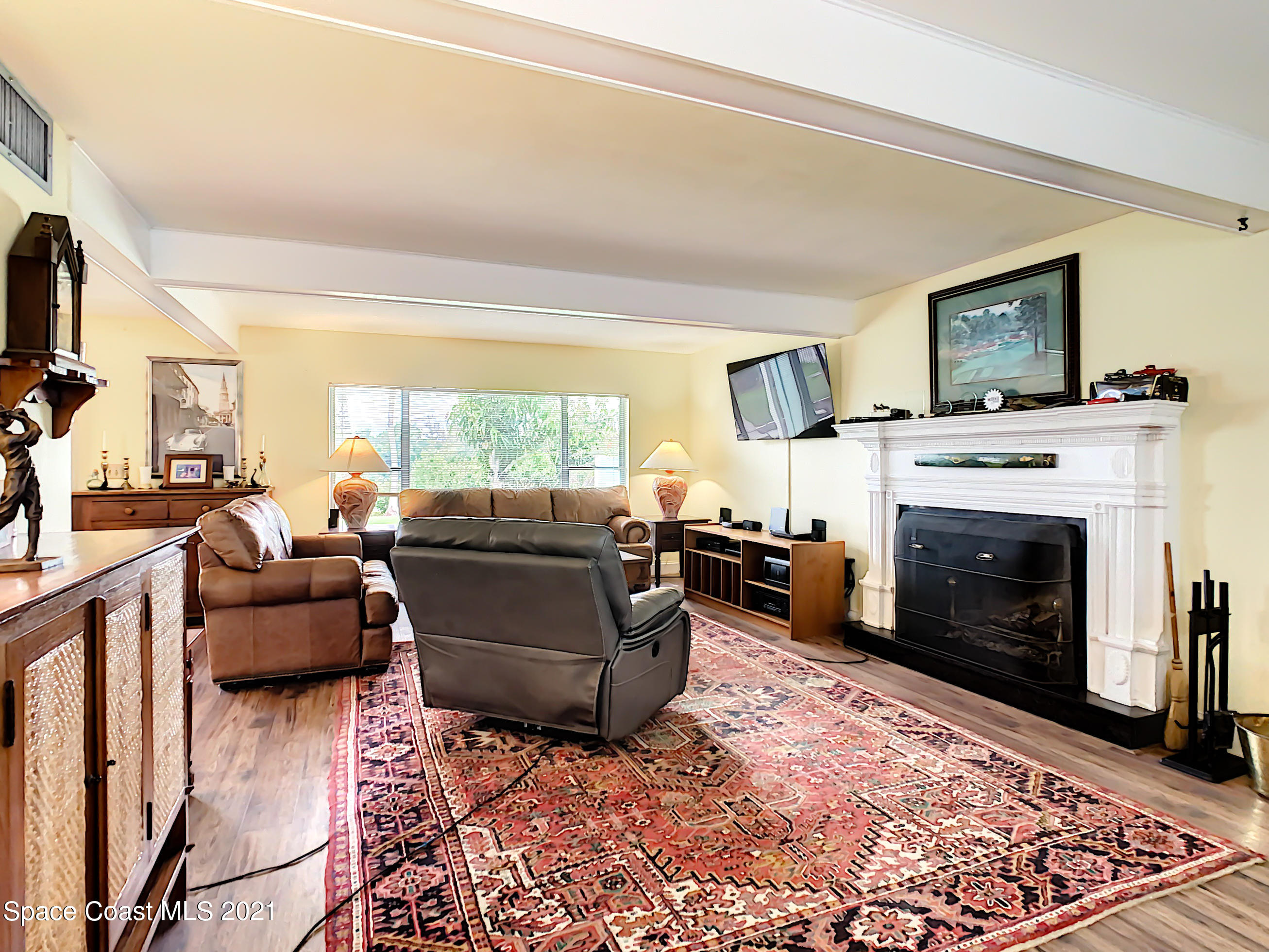 738 Nassau Road Cocoa Beach, FL 32931 - Photo 5 of 26 a living room with furniture a flat screen tv and a fireplace