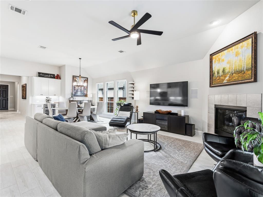 15340 Crape Myrtle Road Frisco, TX 75035 - Photo 4 of 40 Vaulted ceilings above a living area featuring a fireplace with a tile surround and a contemporary ceiling fan