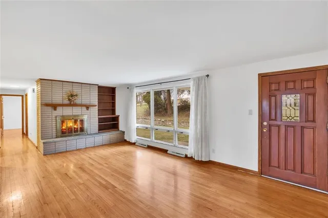 an empty room with wooden floor fireplace and windows
