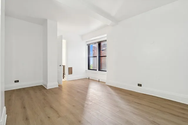 an empty room with wooden floor and window
