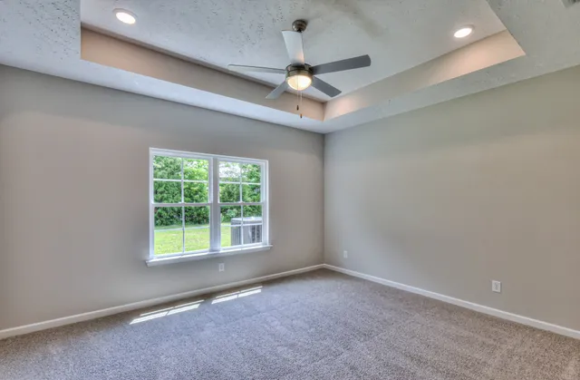 an empty room with a window and a ceiling fan