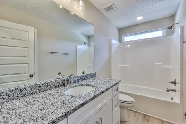 a bathroom with a granite countertop sink a toilet and shower
