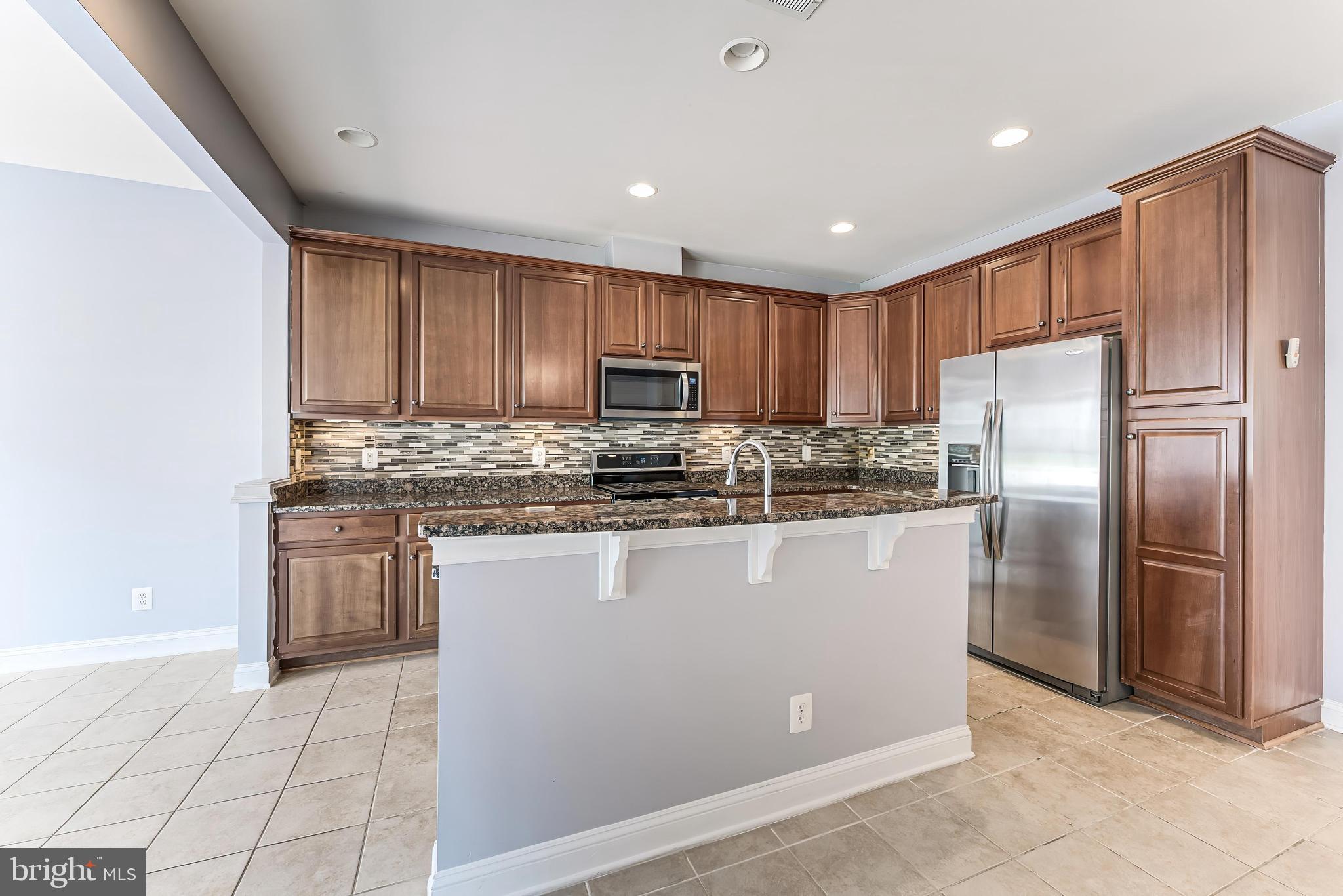 43583 White Cap Terrace Chantilly, VA 20152 - Photo 16 of 55 a kitchen with granite countertop a refrigerator and a stove top oven