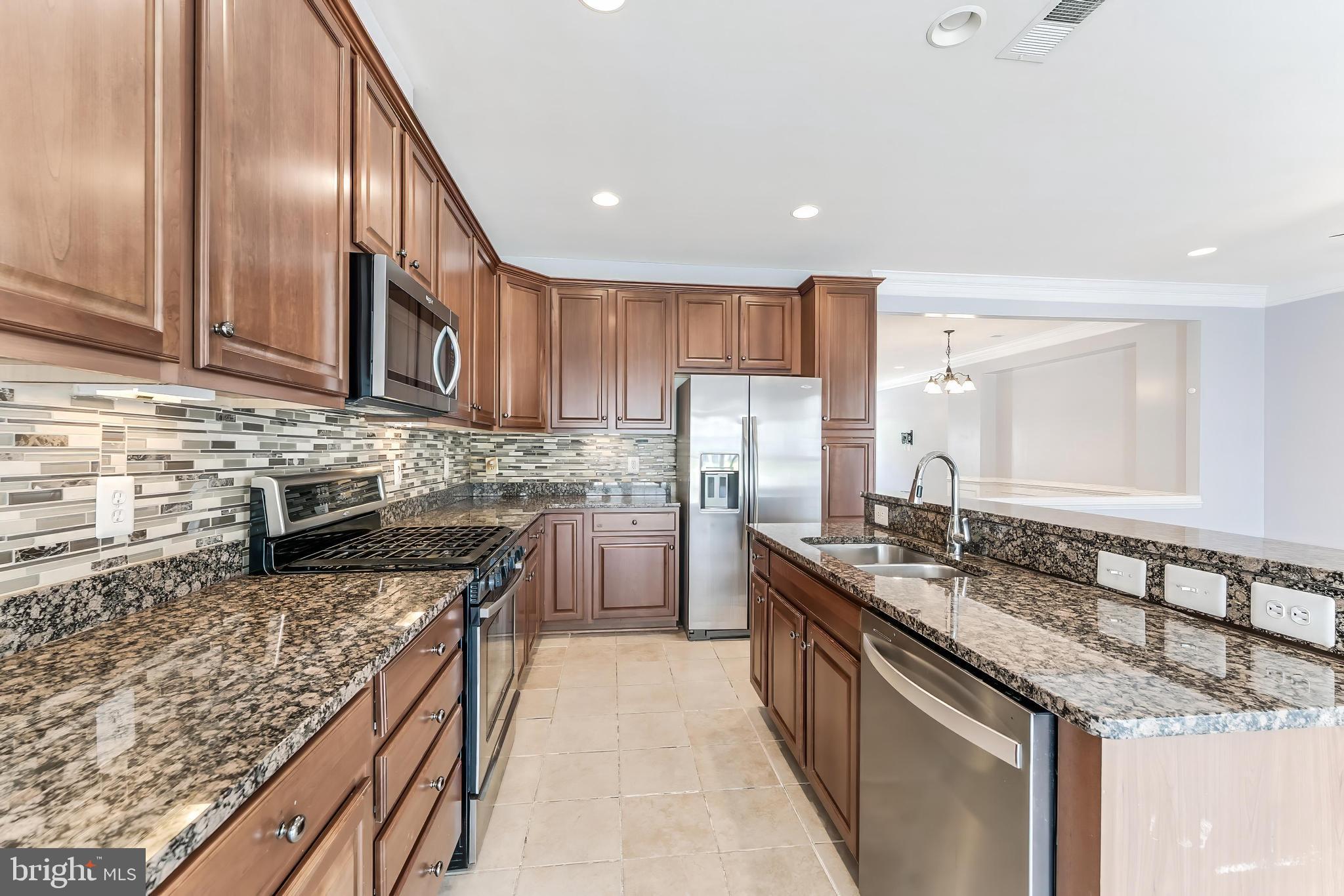 43583 White Cap Terrace Chantilly, VA 20152 - Photo 18 of 55 a kitchen with stainless steel appliances granite countertop a sink a stove and a refrigerator