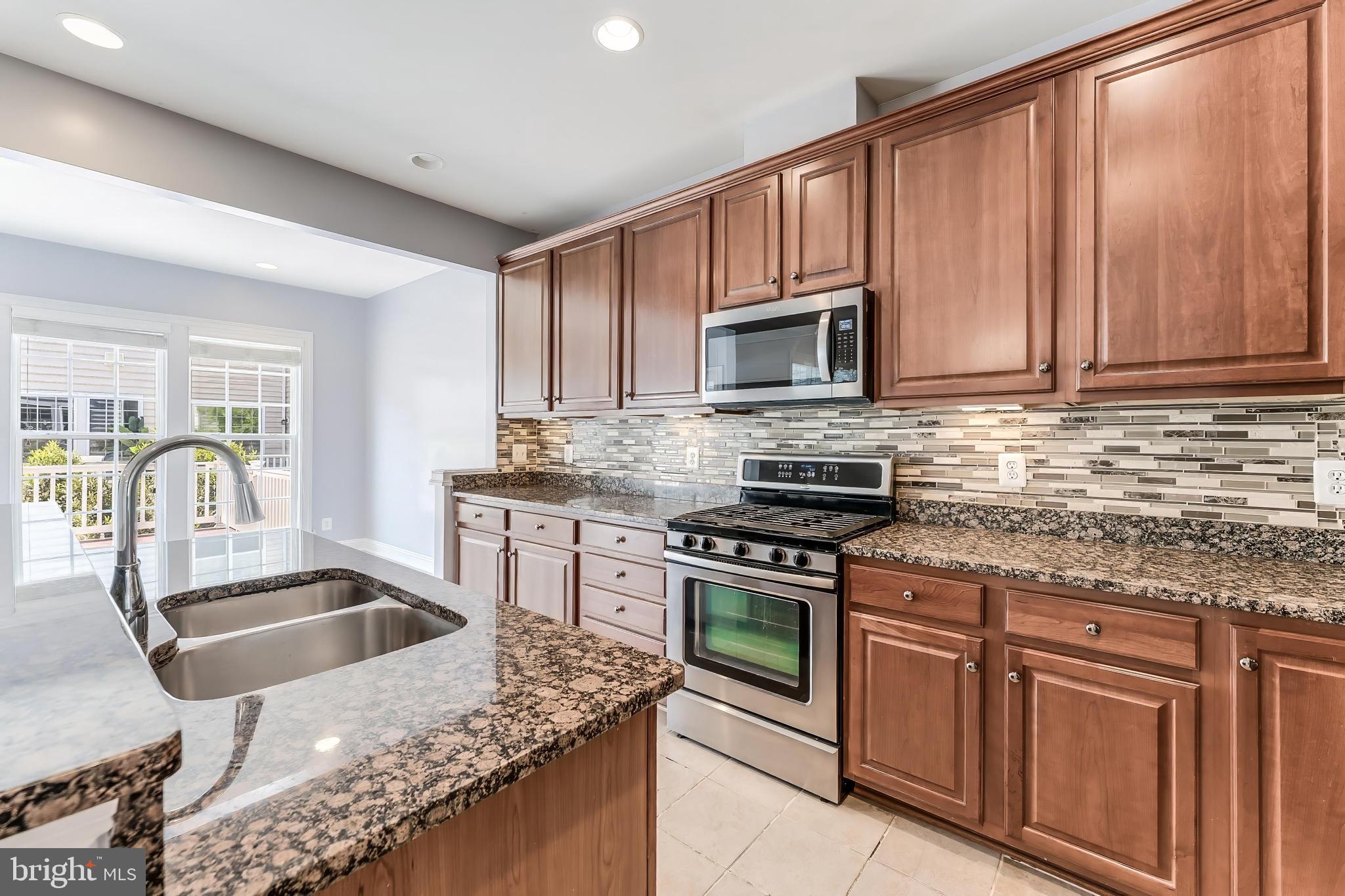 43583 White Cap Terrace Chantilly, VA 20152 - Photo 20 of 55 a kitchen with granite countertop a stove a sink and a microwave