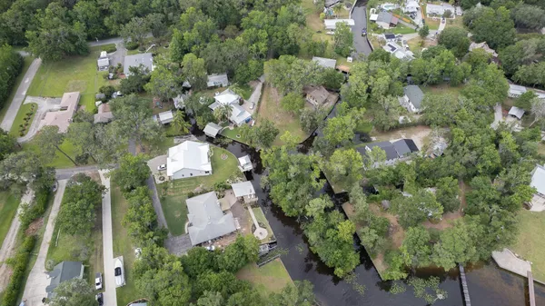 an aerial view of a house with outdoor space and trees all around