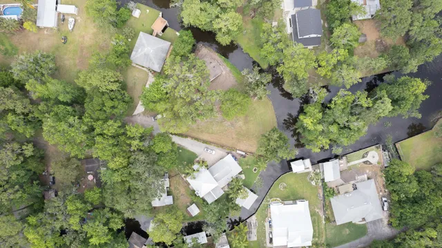 an aerial view of residential house with outdoor space and trees all around