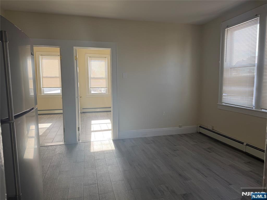 557 Gregory Avenue, Unit 2 Passaic, NJ 07055 - Photo 2 of 9 an empty room with wooden floor and windows