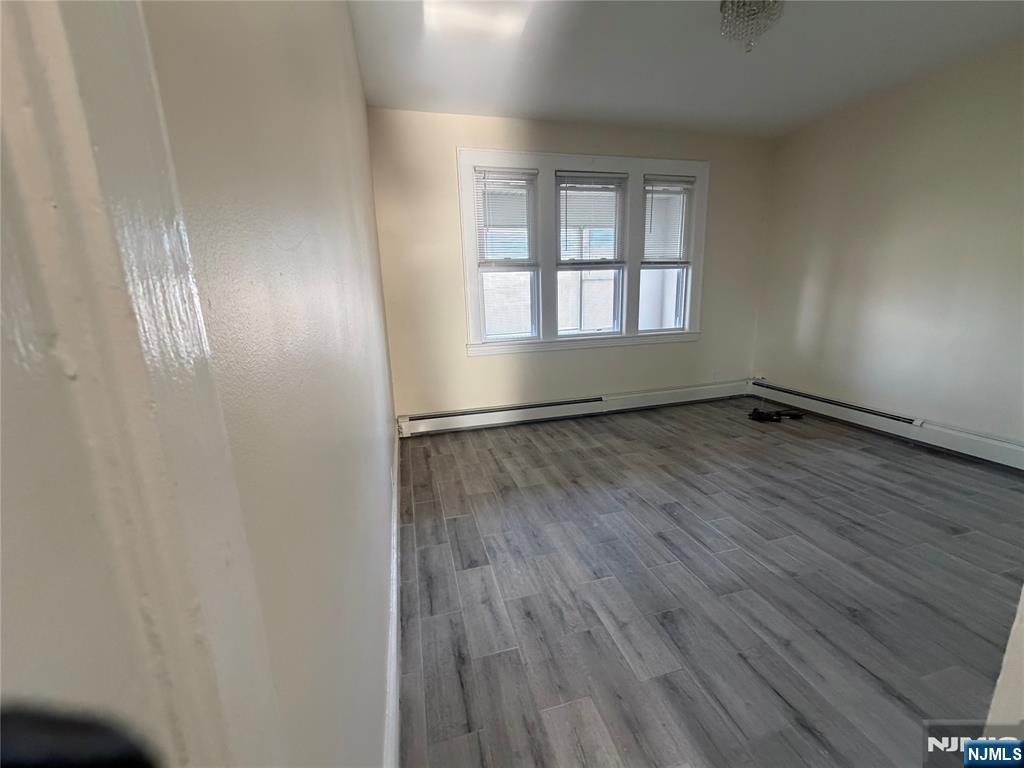 557 Gregory Avenue, Unit 2 Passaic, NJ 07055 - Photo 7 of 9 an empty room with wooden floor and windows