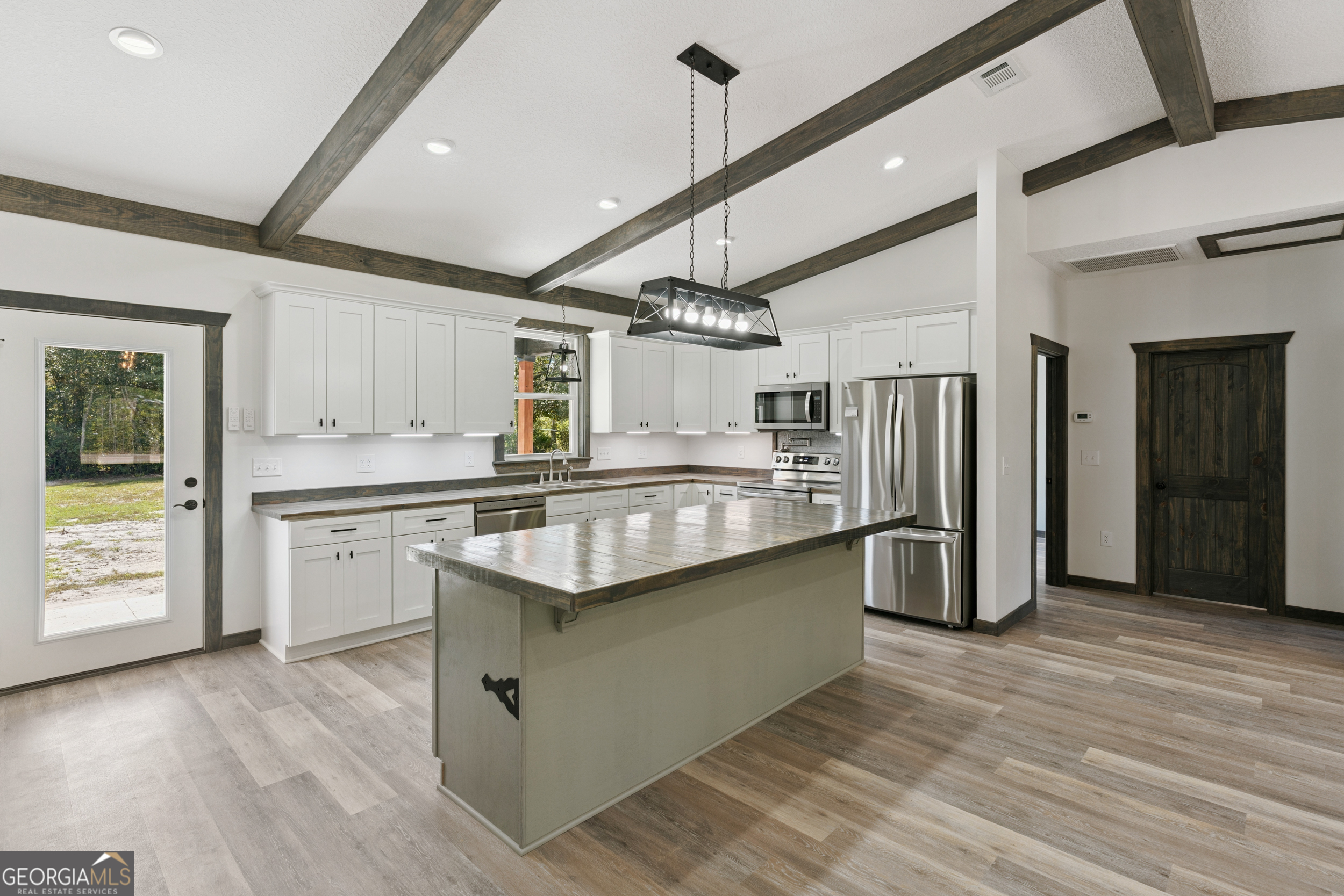 29 Chisholm Street Nahunta, GA 31553 - Photo 12 of 49 a kitchen with stainless steel appliances granite countertop a refrigerator a sink dishwasher a stove and white cabinets with wooden floor